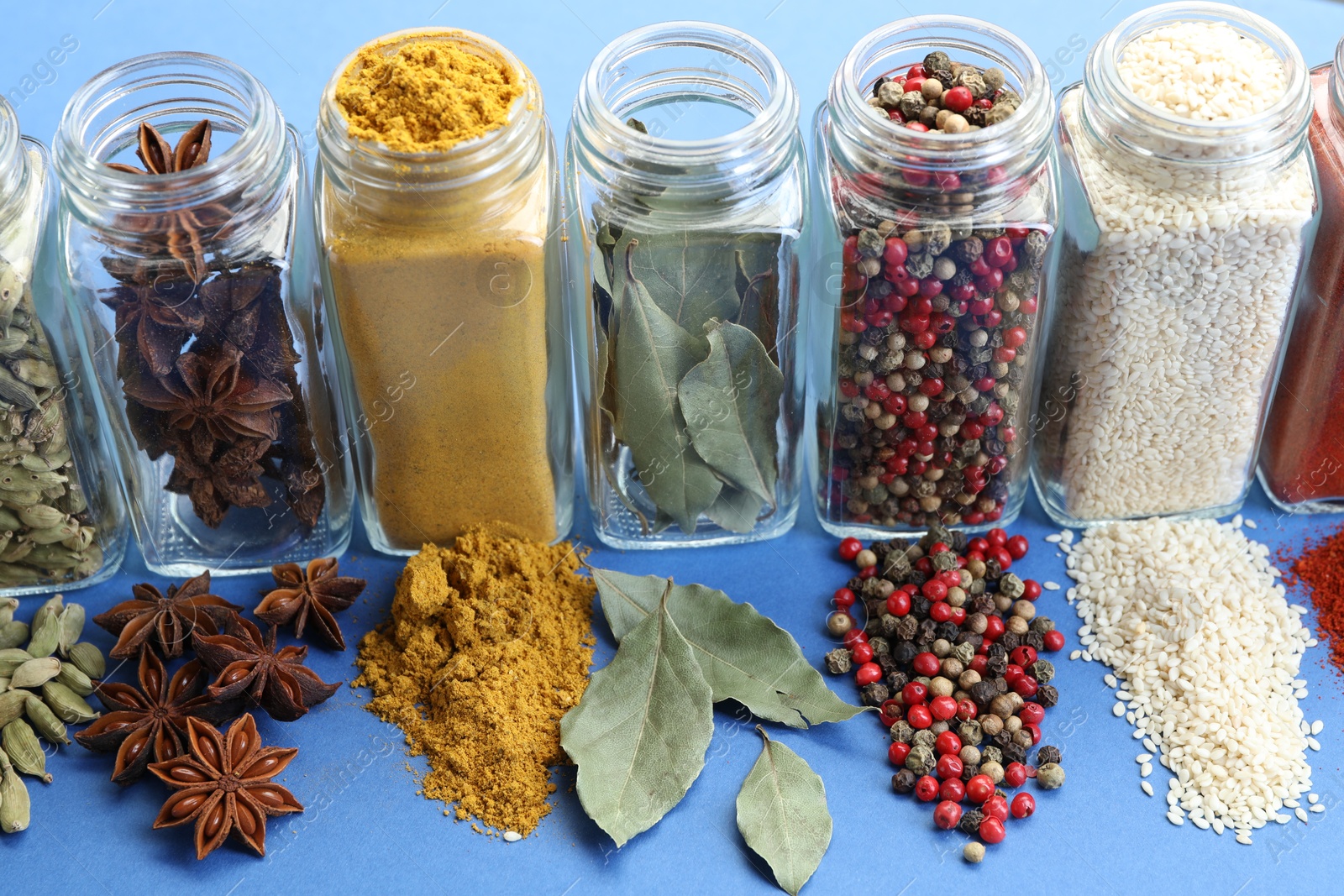Different aromatic spices in jars on blue background, closeup Photo of Different aromatic spices in jars on blue background, closeup