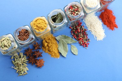 Photo of Different aromatic spices in jars on blue background, flat lay