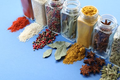 Photo of Different aromatic spices in jars on blue background, closeup