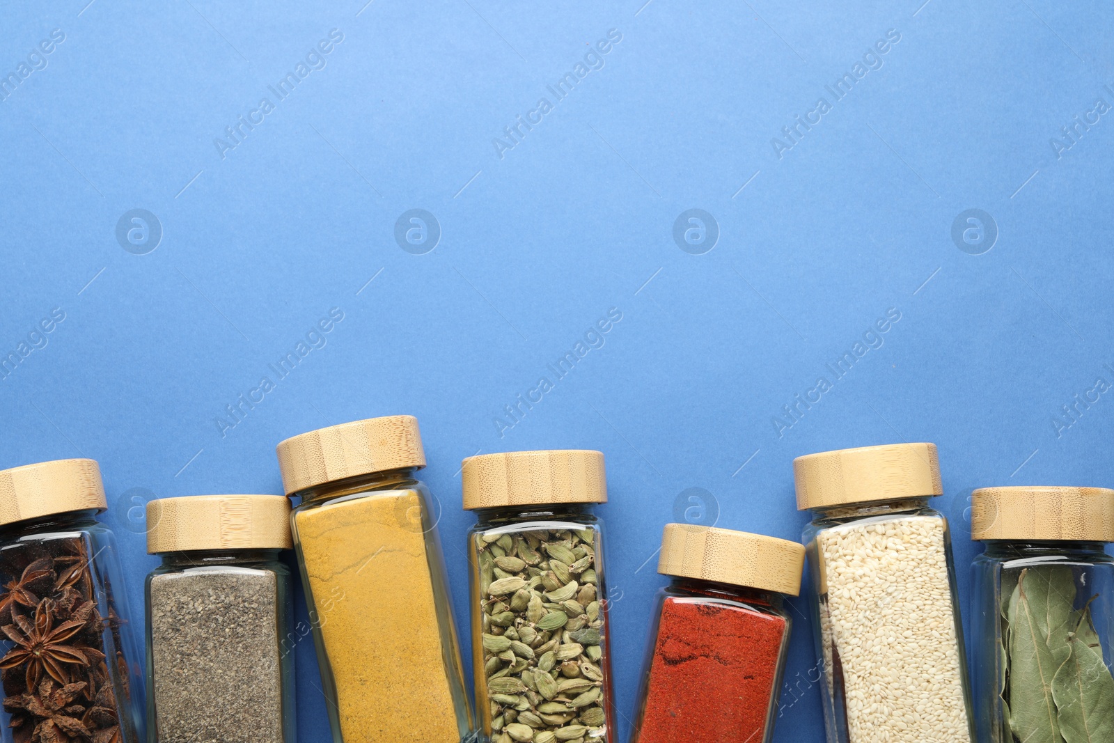Different aromatic spices in jars on blue background, flat lay. Space for text Photo of Different aromatic spices in jars on blue background, flat lay. Space for text