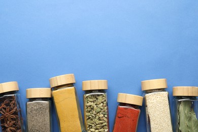 Photo of Different aromatic spices in jars on blue background, flat lay. Space for text