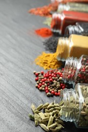 Photo of Different aromatic spices in jars on black table, closeup