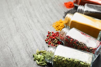 Photo of Different aromatic spices in jars on black table, closeup. Space for text