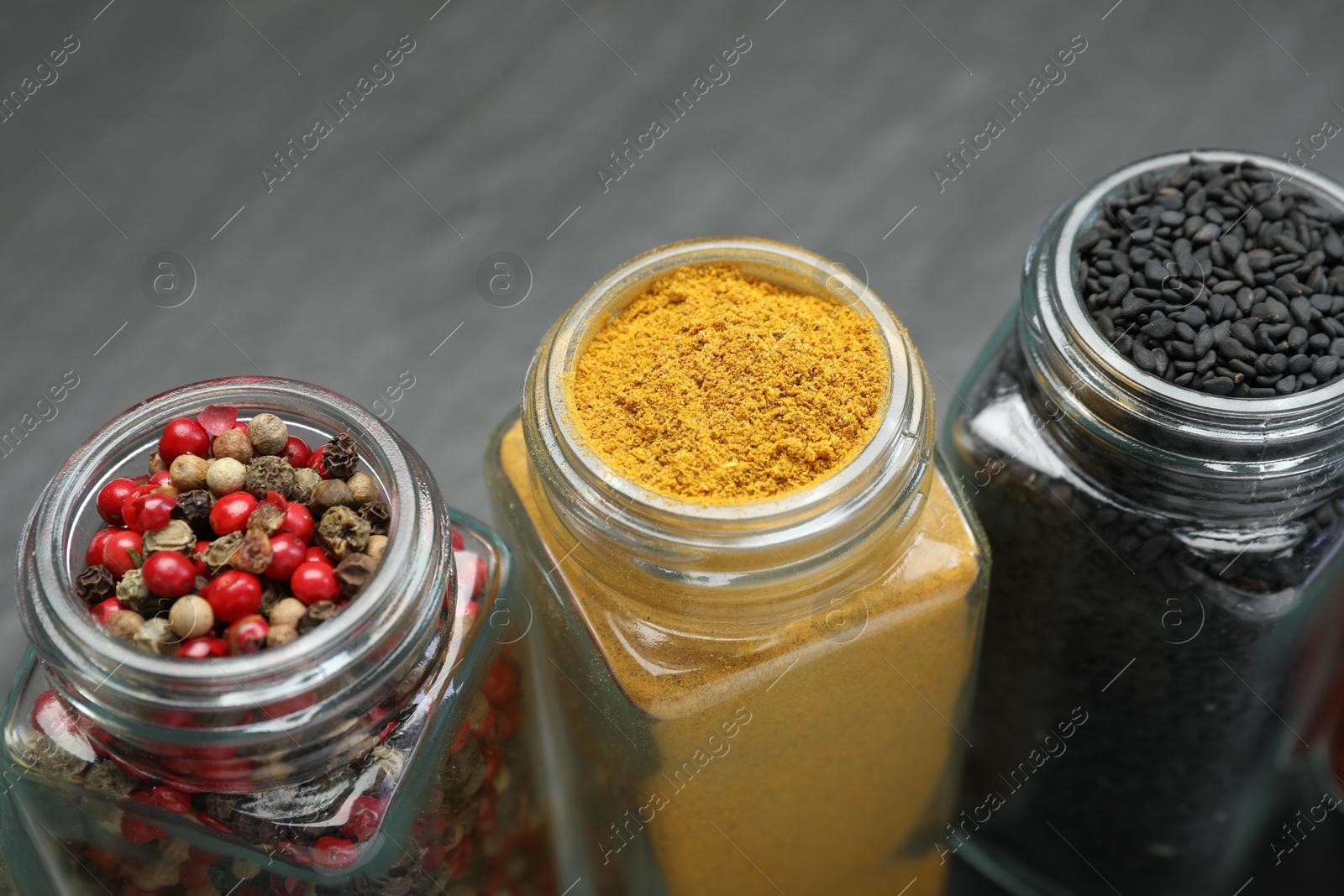 Different aromatic spices in jars on black table, closeup Photo of Different aromatic spices in jars on black table, closeup