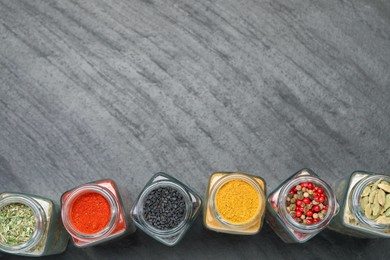 Photo of Different aromatic spices in jars on black table, flat lay. Space for text