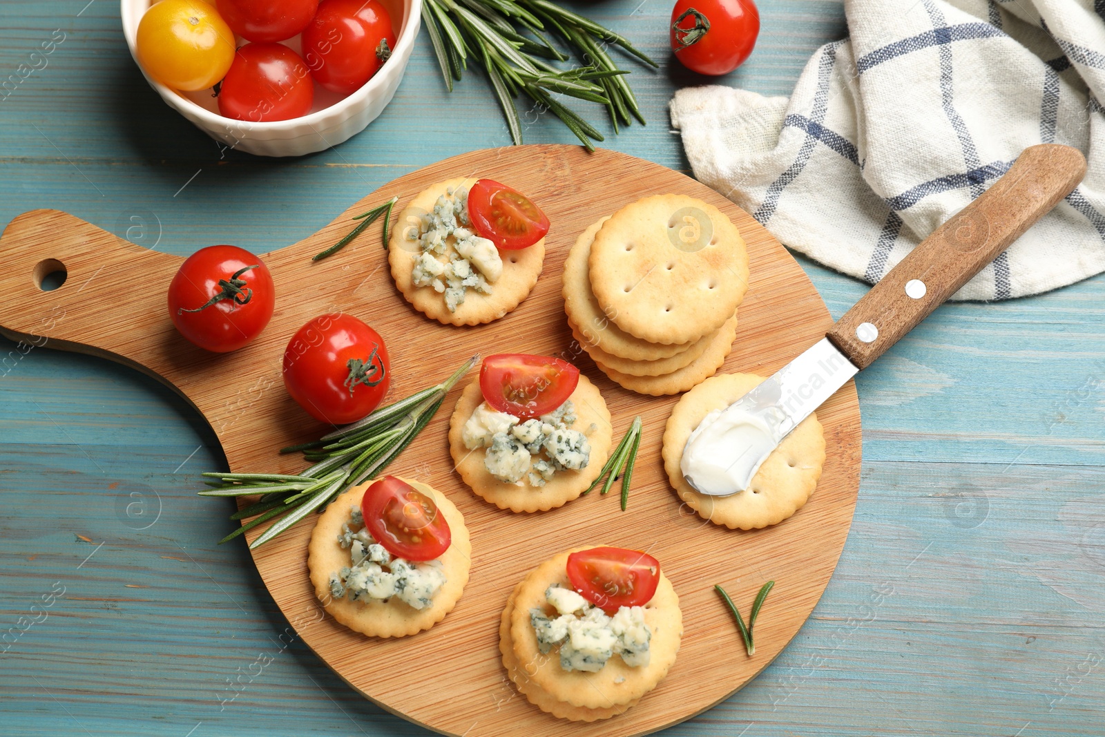 Tasty crackers with blue cheese, rosemary and tomatoes on wooden table, flat lay Photo of Tasty crackers with blue cheese, rosemary and tomatoes on wooden table, flat lay