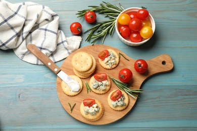 Photo of Tasty crackers with blue cheese, rosemary and tomatoes on wooden table, flat lay