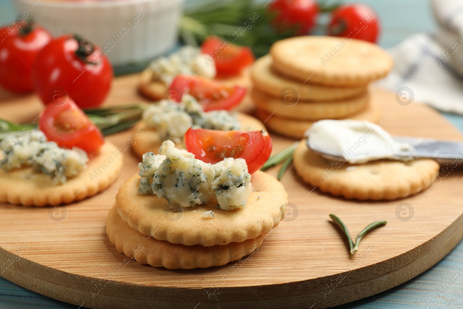 Tasty crackers with blue cheese, rosemary and tomatoes on wooden table, closeup Photo of Tasty crackers with blue cheese, rosemary and tomatoes on wooden table, closeup