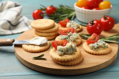 Photo of Tasty crackers with blue cheese, rosemary and tomatoes on wooden table, closeup