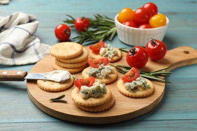 Photo of Tasty crackers with blue cheese, rosemary and tomatoes on wooden table, closeup