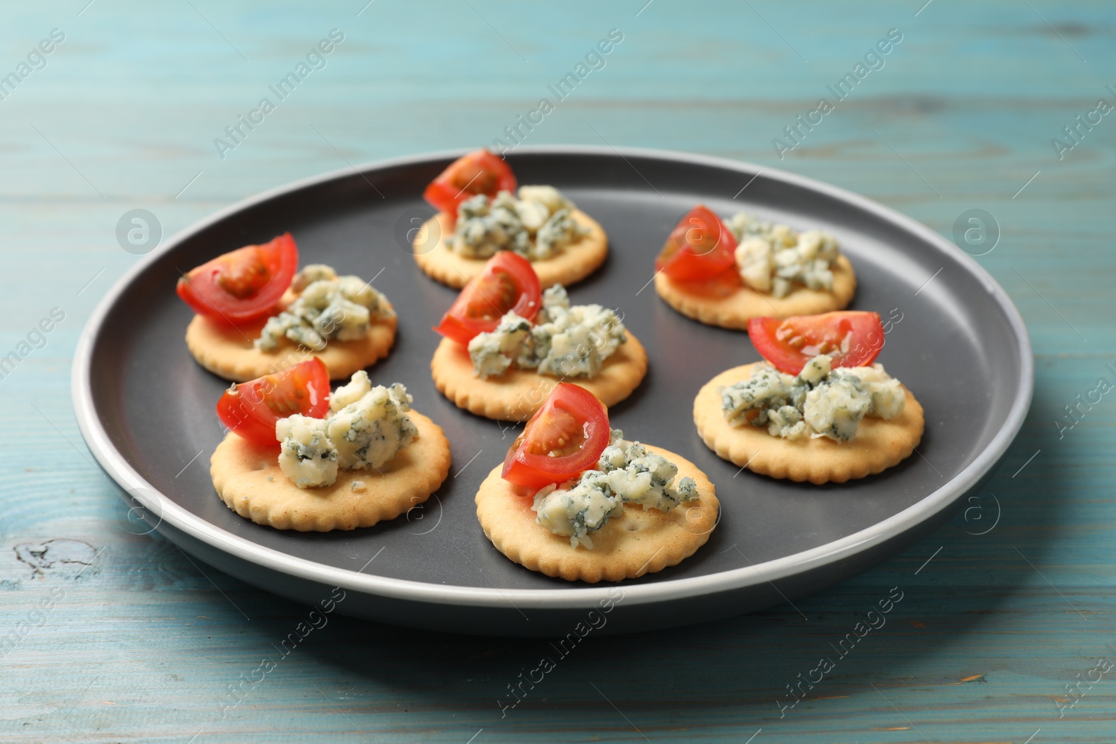Tasty crackers with blue cheese and tomatoes on wooden table, closeup Photo of Tasty crackers with blue cheese and tomatoes on wooden table, closeup