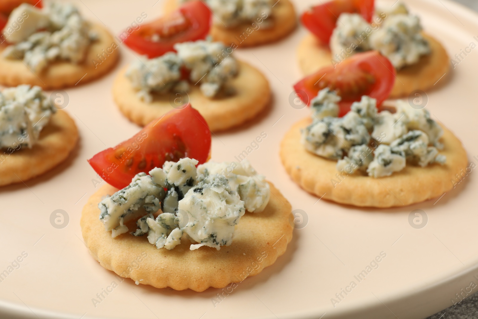 Tasty crackers with blue cheese and tomatoes on plate, closeup Photo of Tasty crackers with blue cheese and tomatoes on plate, closeup