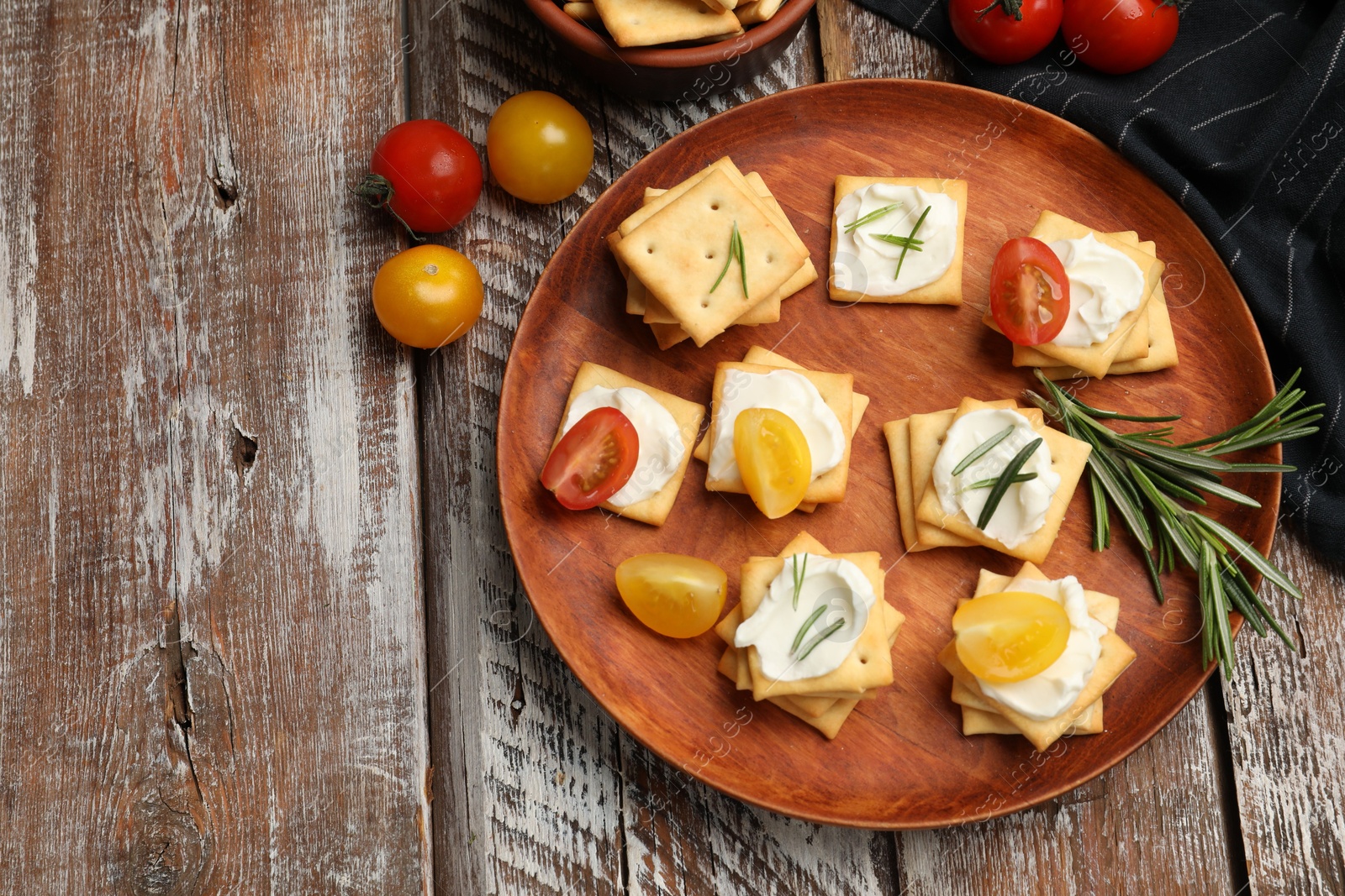 Tasty crackers with cream cheese, rosemary and tomatoes on wooden table, flat lay. Space for text Photo of Tasty crackers with cream cheese, rosemary and tomatoes on wooden table, flat lay. Space for text