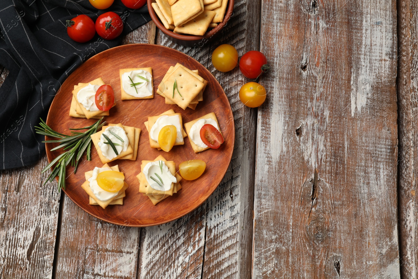 Tasty crackers with cream cheese, rosemary and tomatoes on wooden table, flat lay. Space for text Photo of Tasty crackers with cream cheese, rosemary and tomatoes on wooden table, flat lay. Space for text