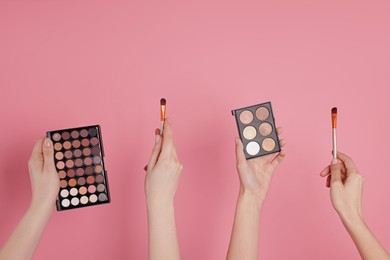 Photo of Women with eyeshadow palettes and brushes on pink background, closeup. Space for text