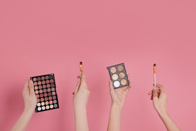 Photo of Women with eyeshadow palettes and brushes on pink background, closeup. Space for text