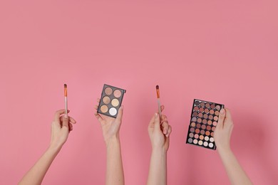 Photo of Women with eyeshadow palettes and brushes on pink background, closeup. Space for text