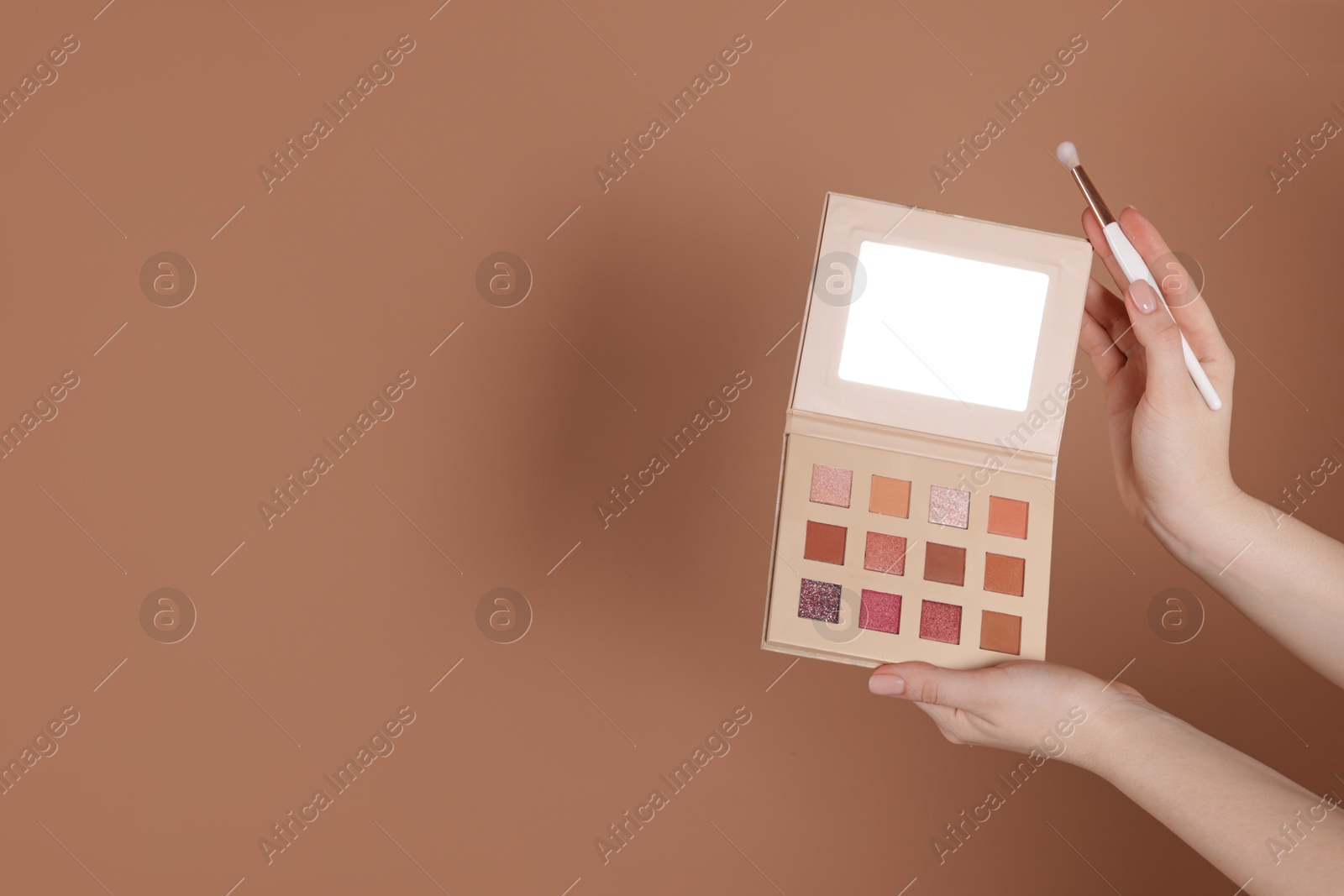 Woman with eyeshadow palette and brush on beige background, closeup. Space for text Photo of Woman with eyeshadow palette and brush on beige background, closeup. Space for text