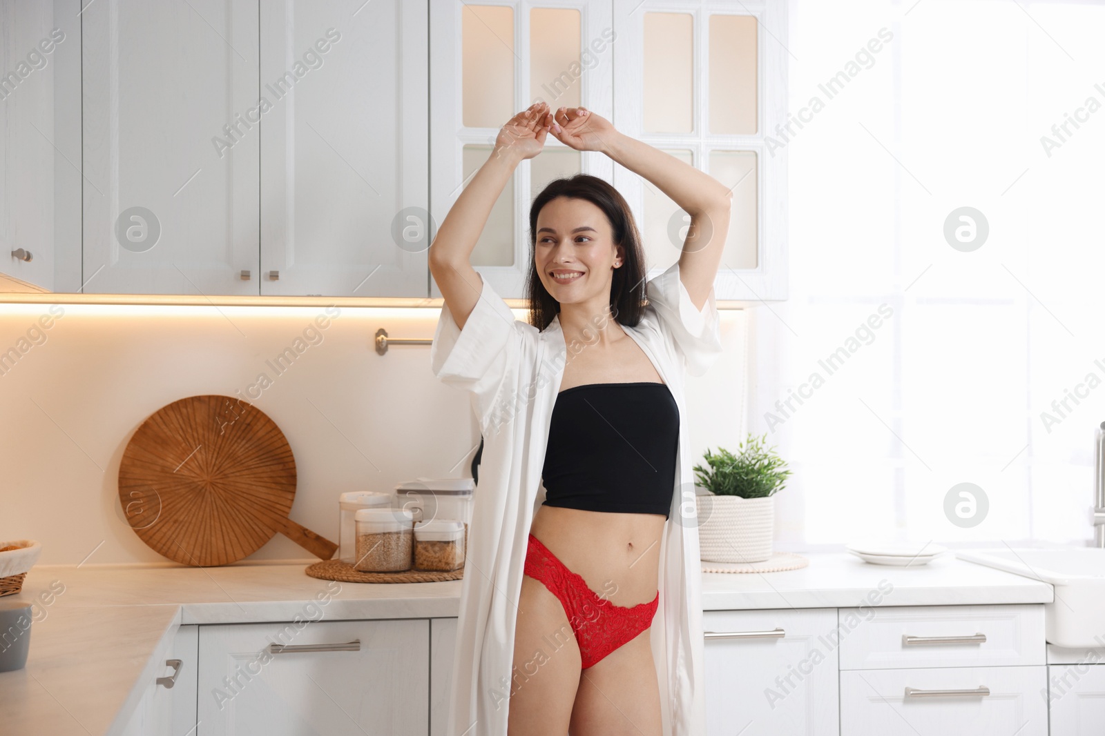 Photo of Woman wearing beautiful lace underwear in kitchen
