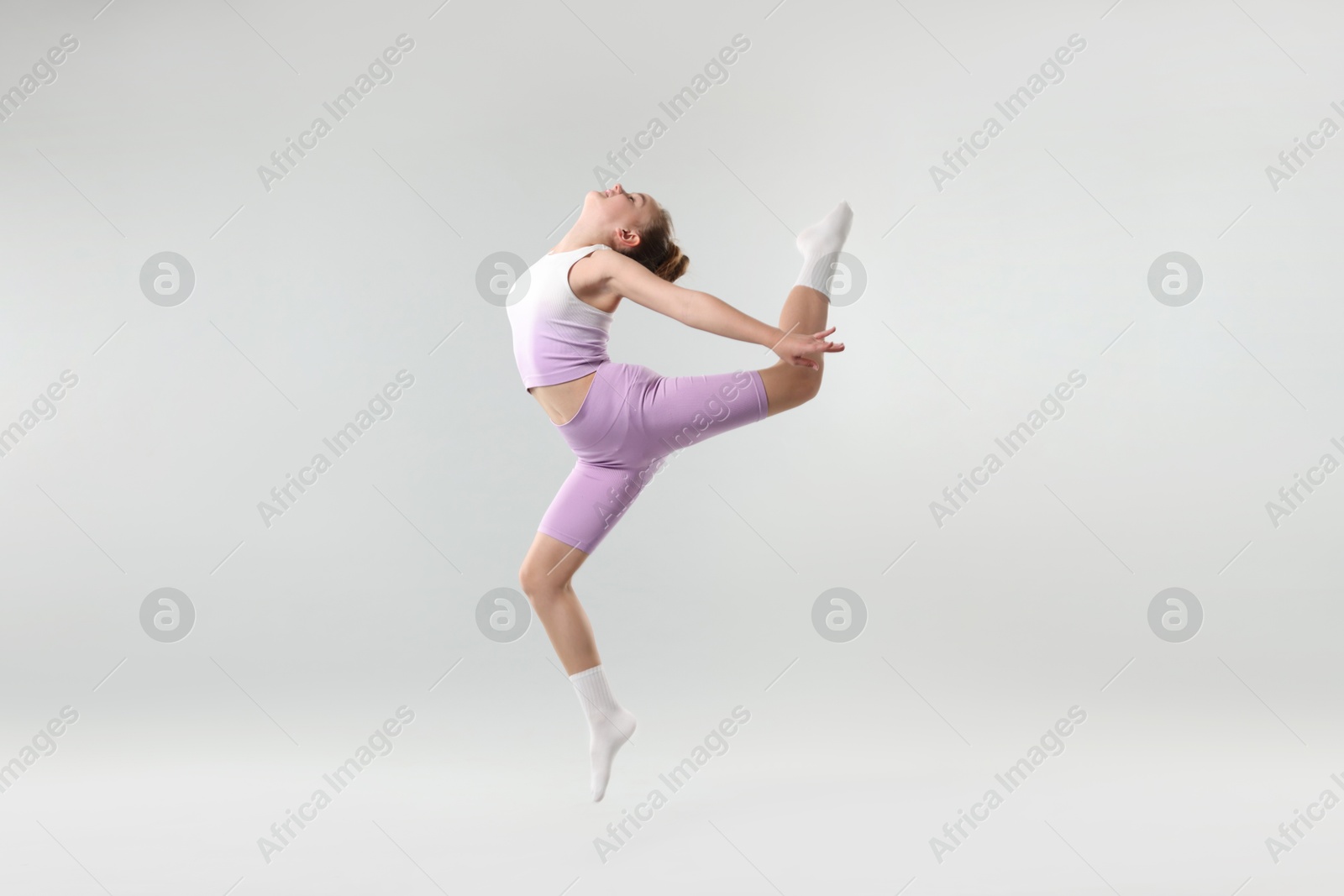 Photo of Girl in stylish clothes dancing on light grey background