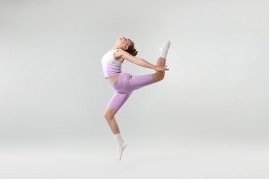 Photo of Girl in stylish clothes dancing on light grey background