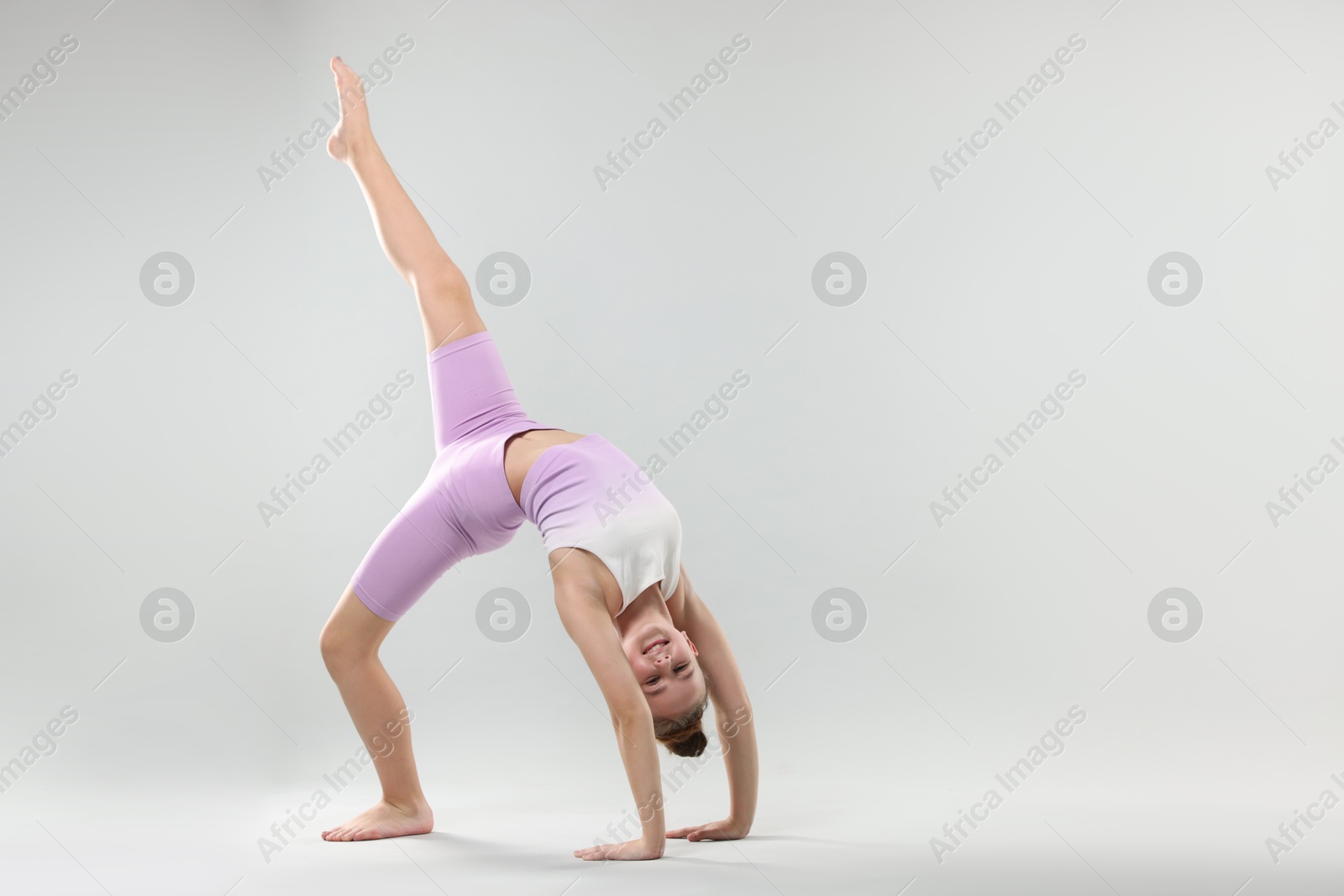 Girl in stylish clothes dancing on light grey background, space for text Photo of Girl in stylish clothes dancing on light grey background, space for text