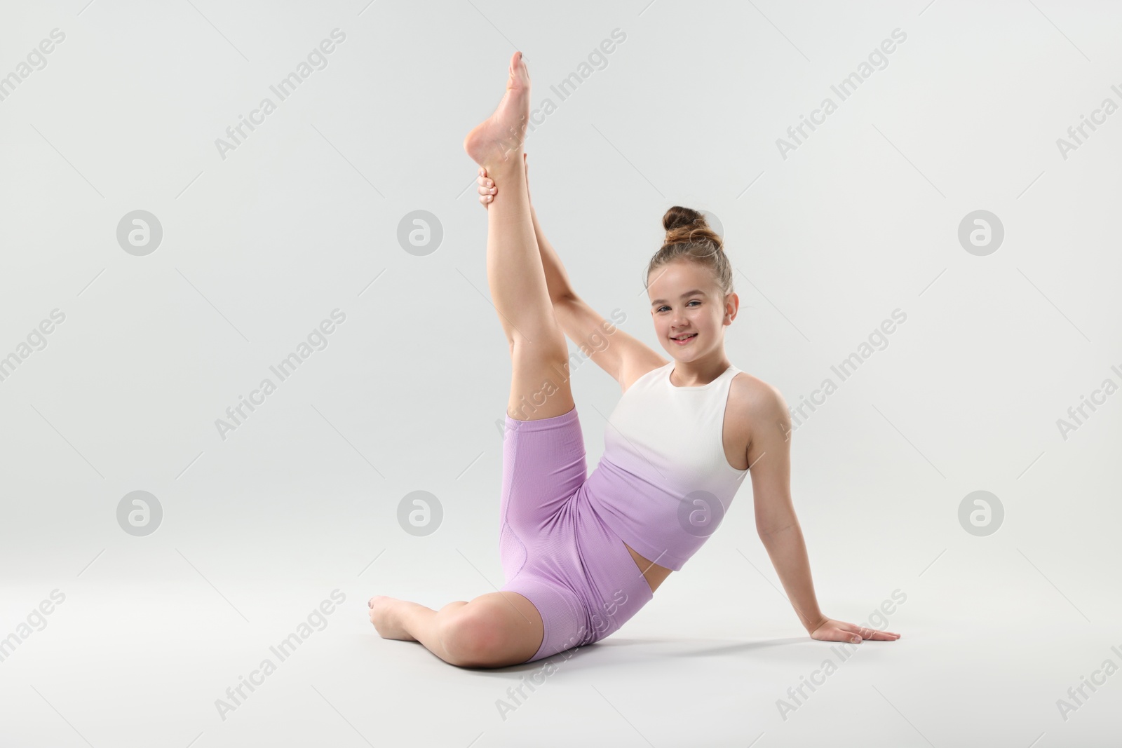 Photo of Girl in stylish clothes stretching on light grey background, space for text. Dance