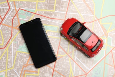 Photo of Road trip concept. Smartphone and car model on city map, top view
