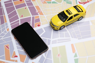 Photo of Road trip concept. Smartphone and car model on city map