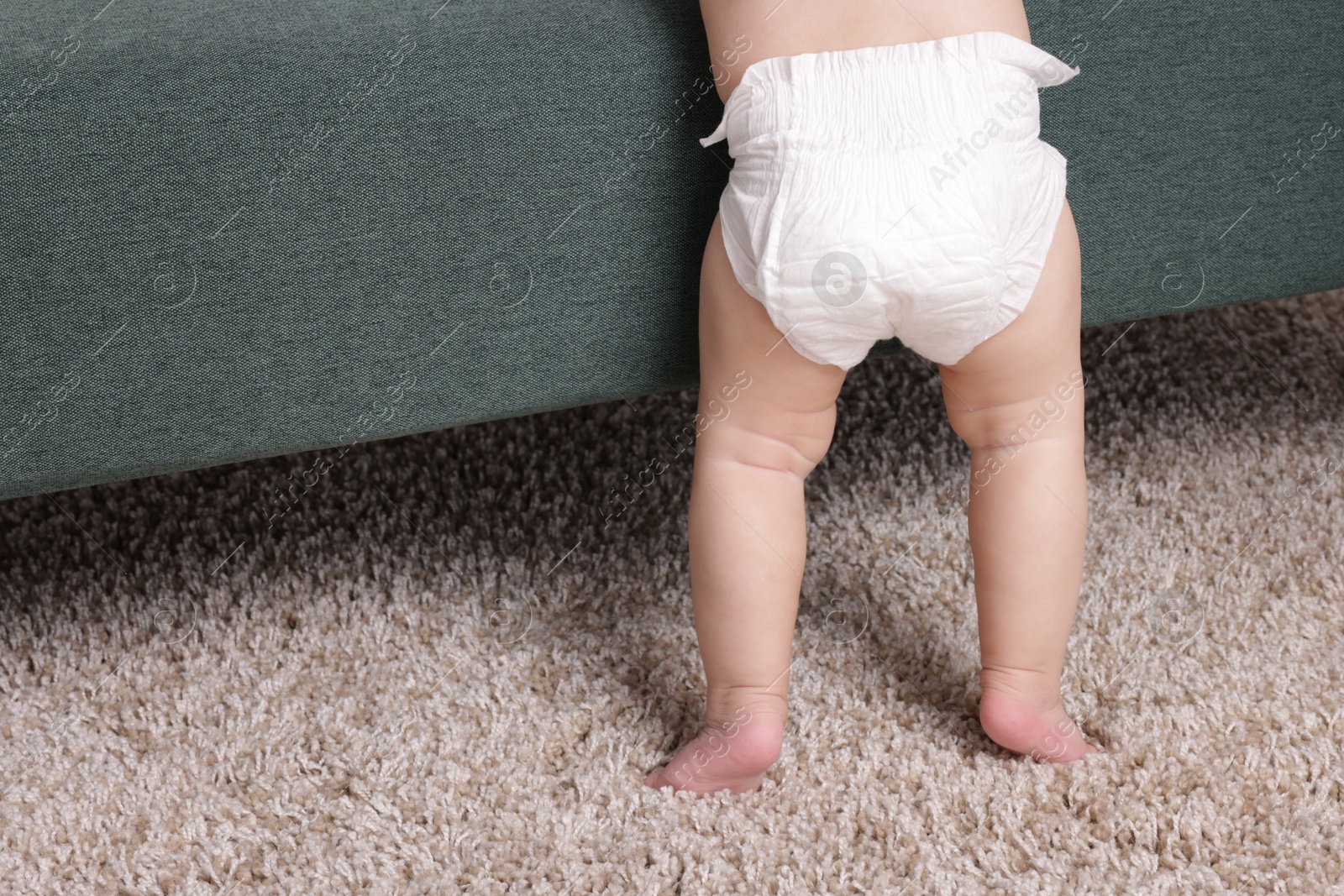 Cute little baby standing near sofa at home, closeup. Space for text Photo of Cute little baby standing near sofa at home, closeup. Space for text