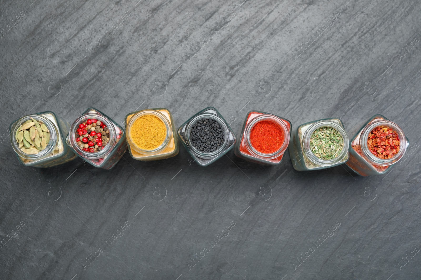 Different aromatic spices in jars on black table, flat lay Photo of Different aromatic spices in jars on black table, flat lay