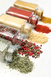 Photo of Different aromatic spices in jars on white table, closeup