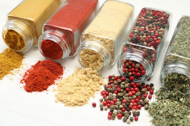 Photo of Different aromatic spices in jars on white table, closeup