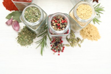 Photo of Different aromatic spices in jars on white table, flat lay