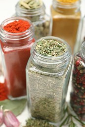 Photo of Different aromatic spices in jars on white table, closeup