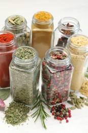 Photo of Different aromatic spices in jars on white table, closeup