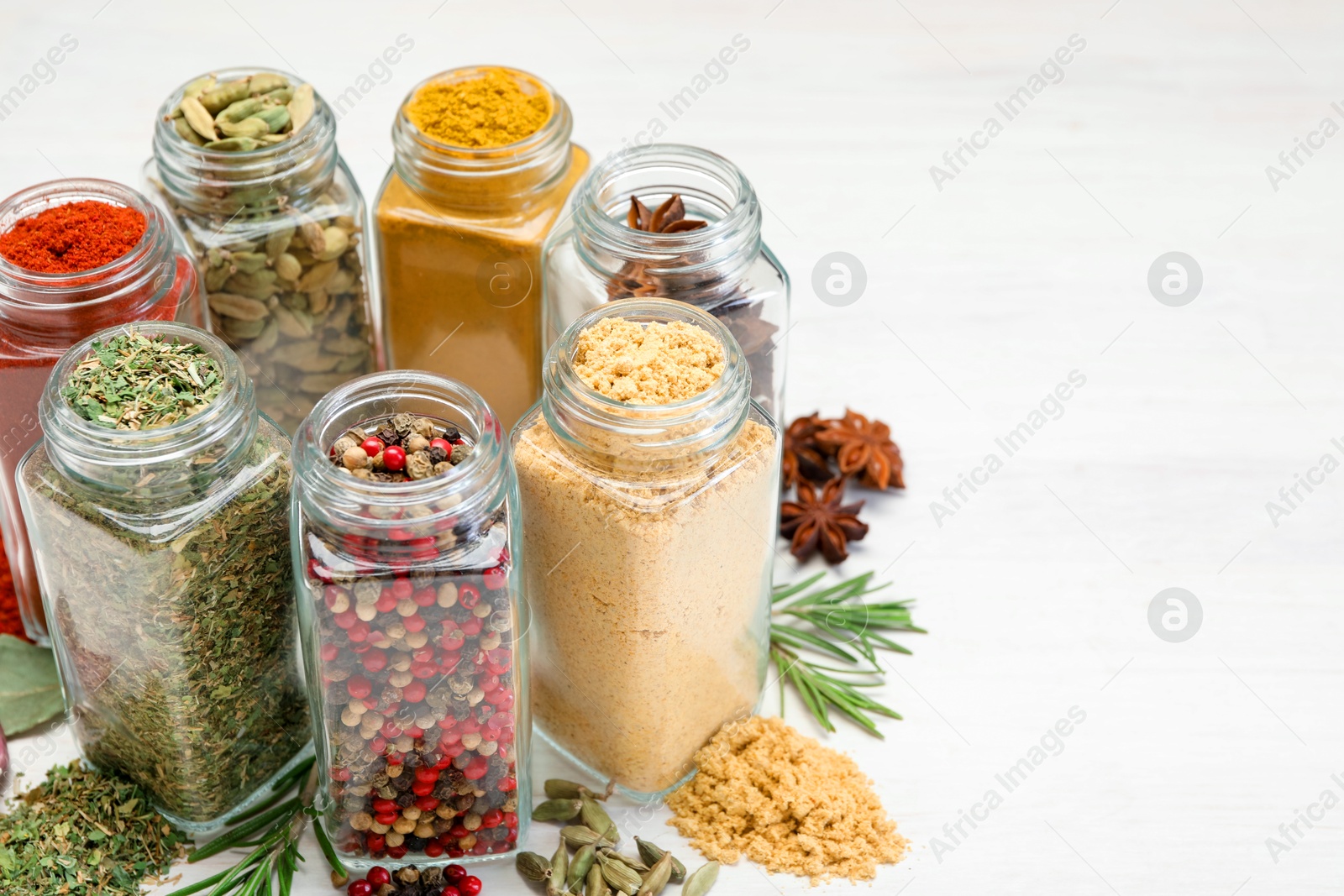 Different aromatic spices in jars on white table, closeup Photo of Different aromatic spices in jars on white table, closeup