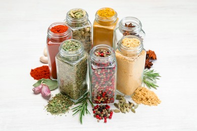 Photo of Different aromatic spices in jars on white table, closeup
