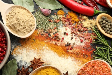 Photo of Different aromatic spices on black background, closeup