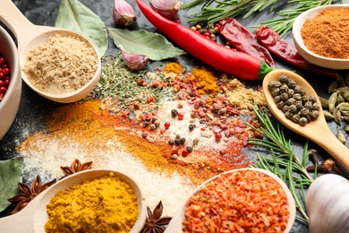 Photo of Different aromatic spices on black background, closeup
