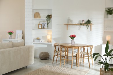 Photo of Stylish dining table with chairs and comfortable sofa in room. Interior design