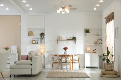 Photo of Stylish dining table with chairs and comfortable sofa in room. Interior design