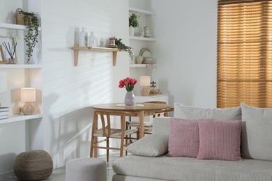 Photo of Stylish dining table with chairs and comfortable sofa in room. Interior design