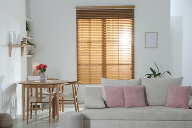 Photo of Stylish dining table with chairs and comfortable sofa in room. Interior design