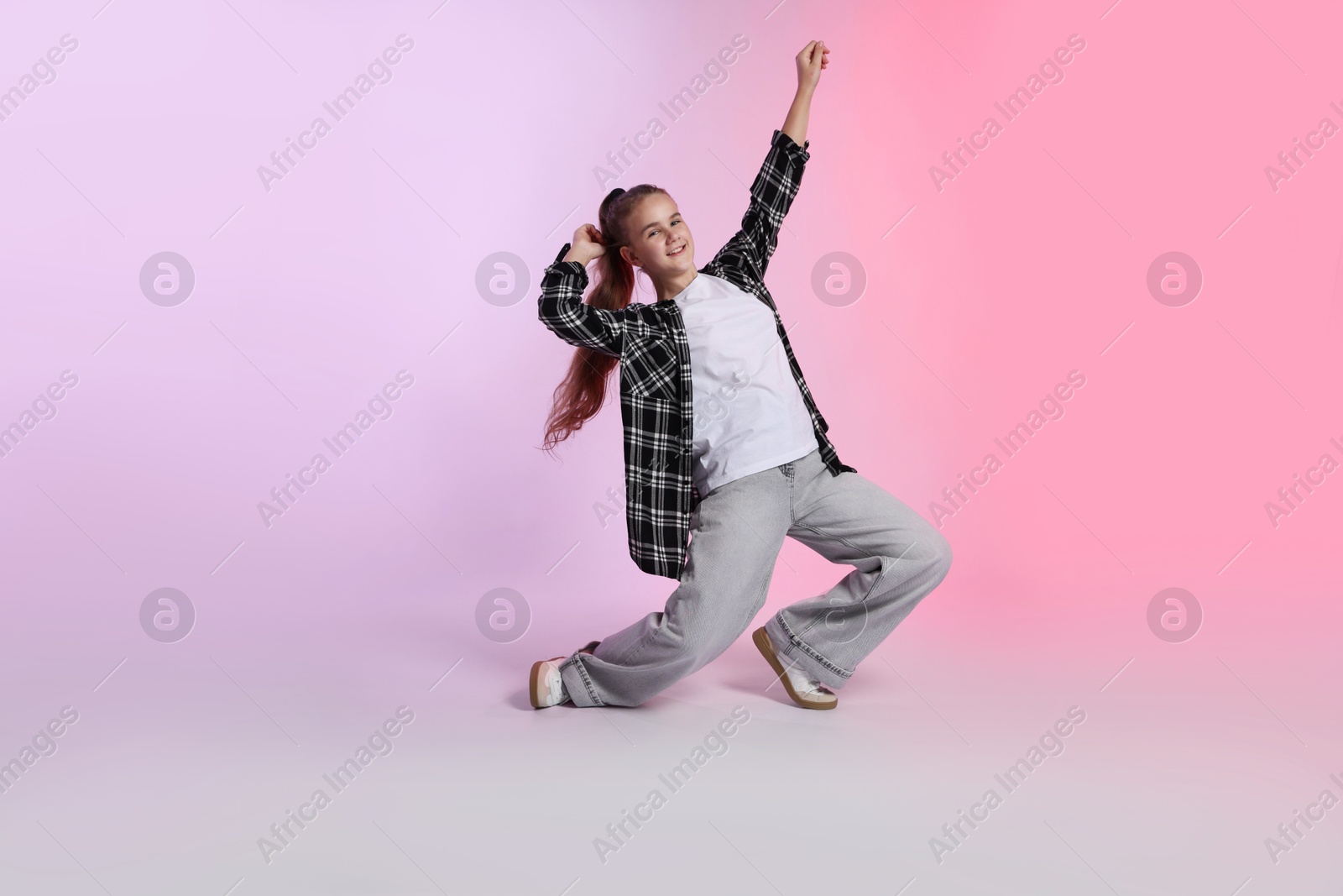 Girl in stylish clothes dancing on color background Photo of Girl in stylish clothes dancing on color background