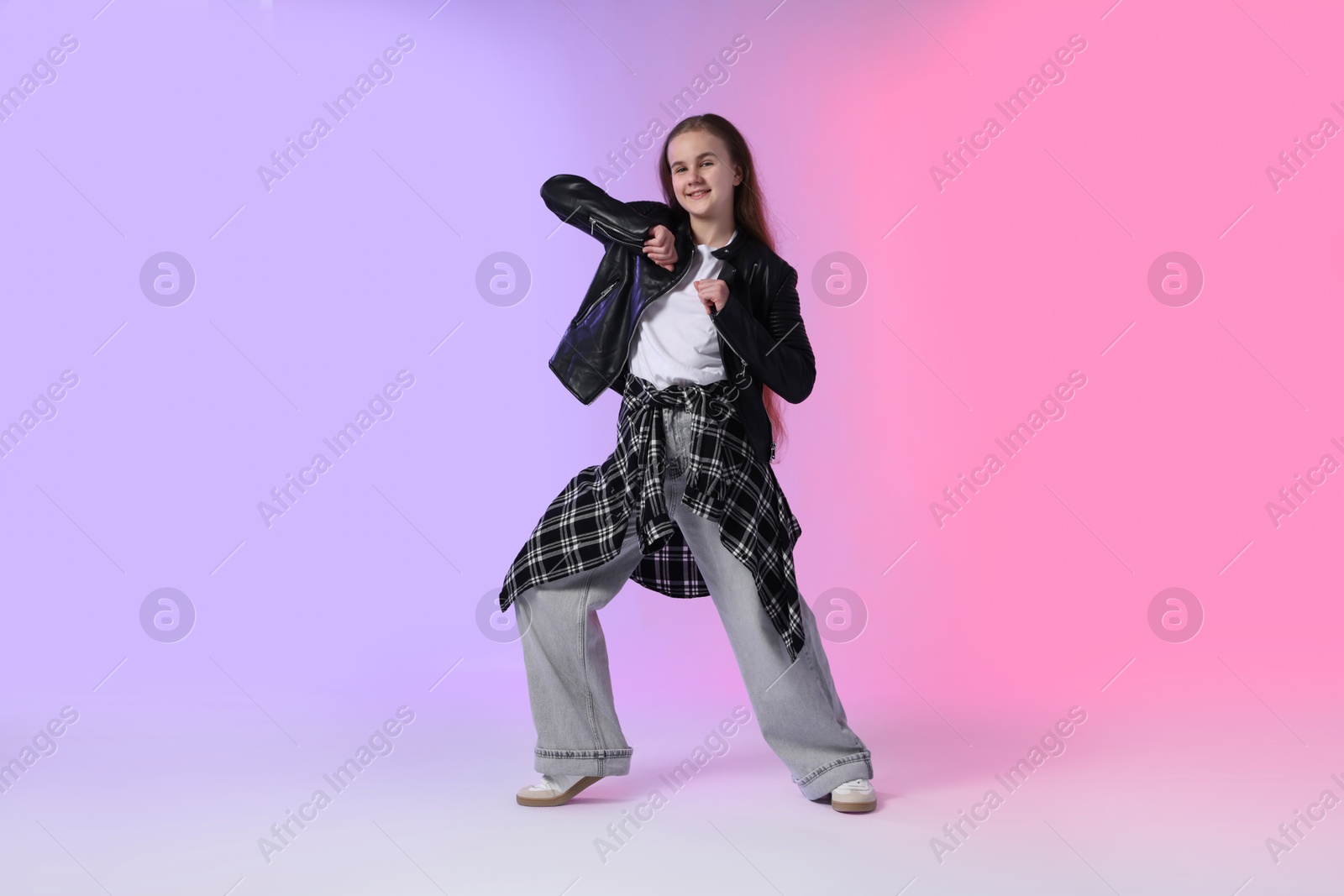 Girl in stylish clothes dancing on color background Photo of Girl in stylish clothes dancing on color background
