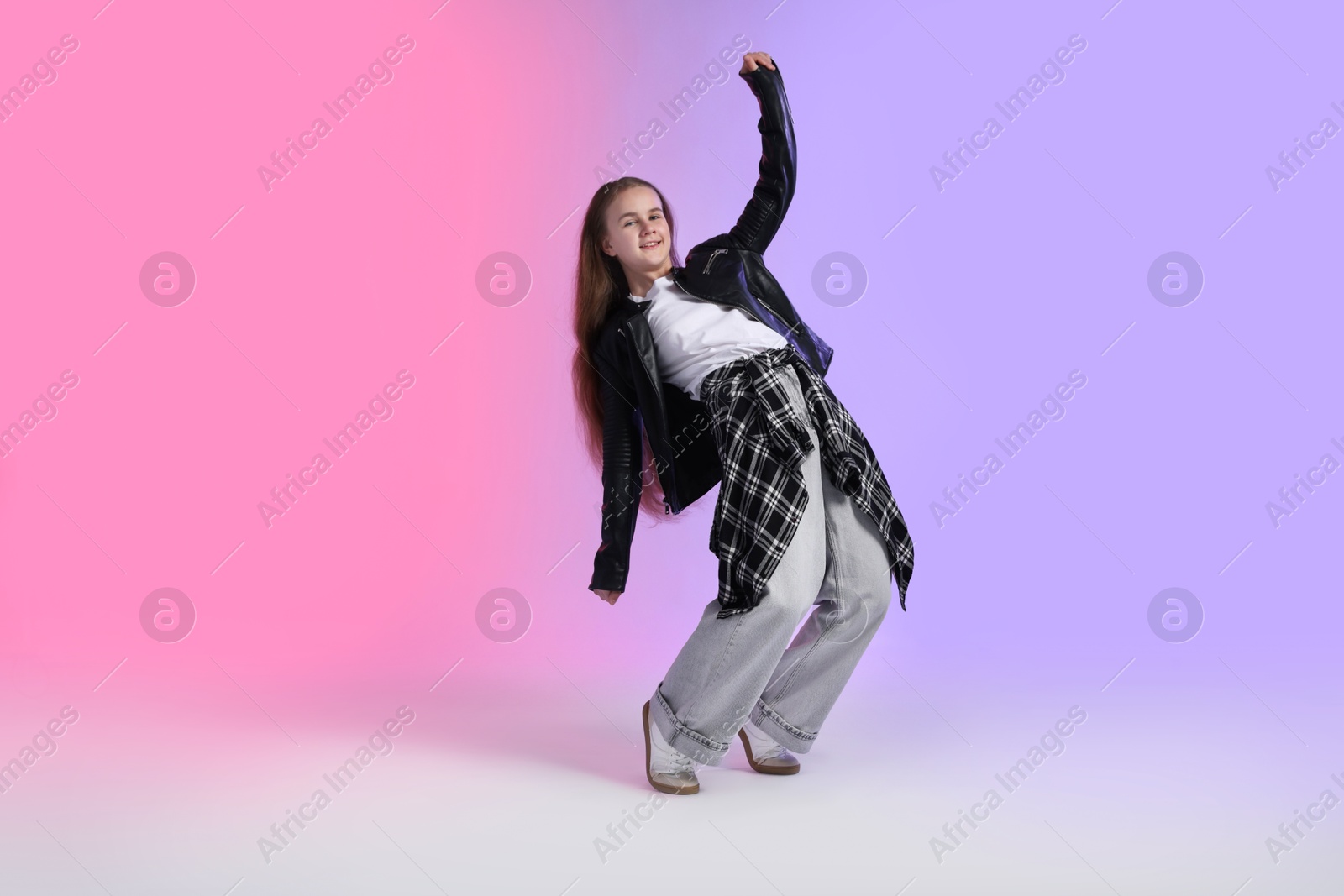 Girl in stylish clothes dancing on color background Photo of Girl in stylish clothes dancing on color background
