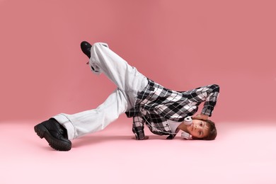 Photo of Boy with headphones in stylish clothes dancing on pink background