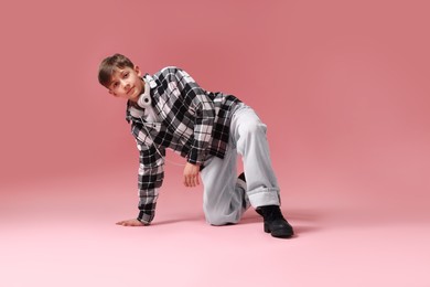 Photo of Boy with headphones in stylish clothes dancing on pink background