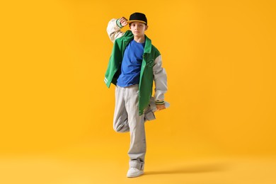 Photo of Boy in stylish clothes dancing on orange background
